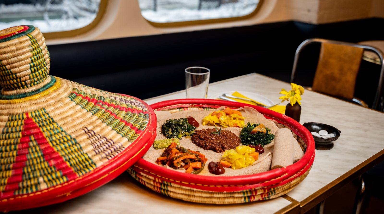 A traditional Habesha mesob basket filled with injera and colorful wats at Makina Cafe